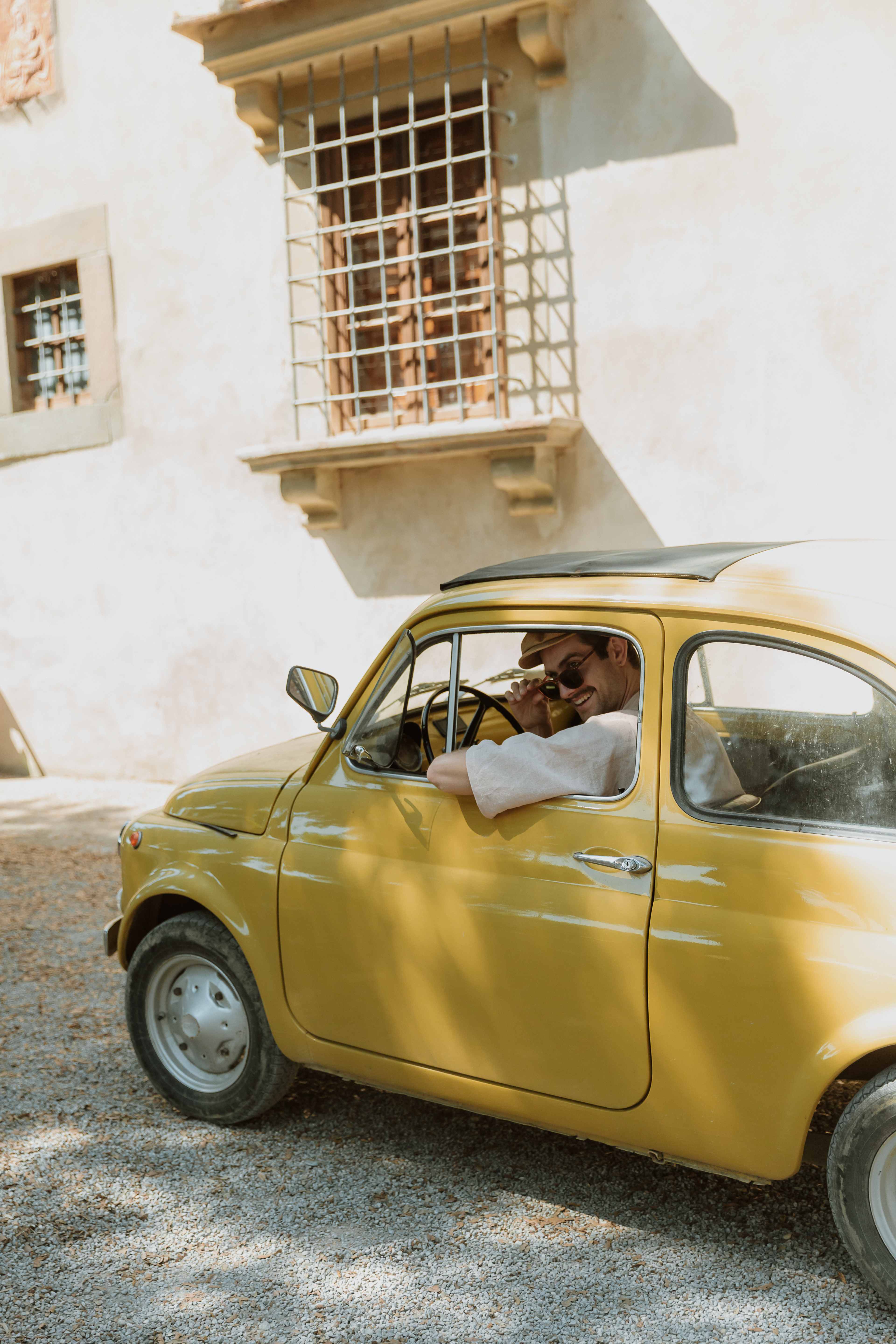 Thomas Wilson in a classic yellow Fiat 500 in Italy