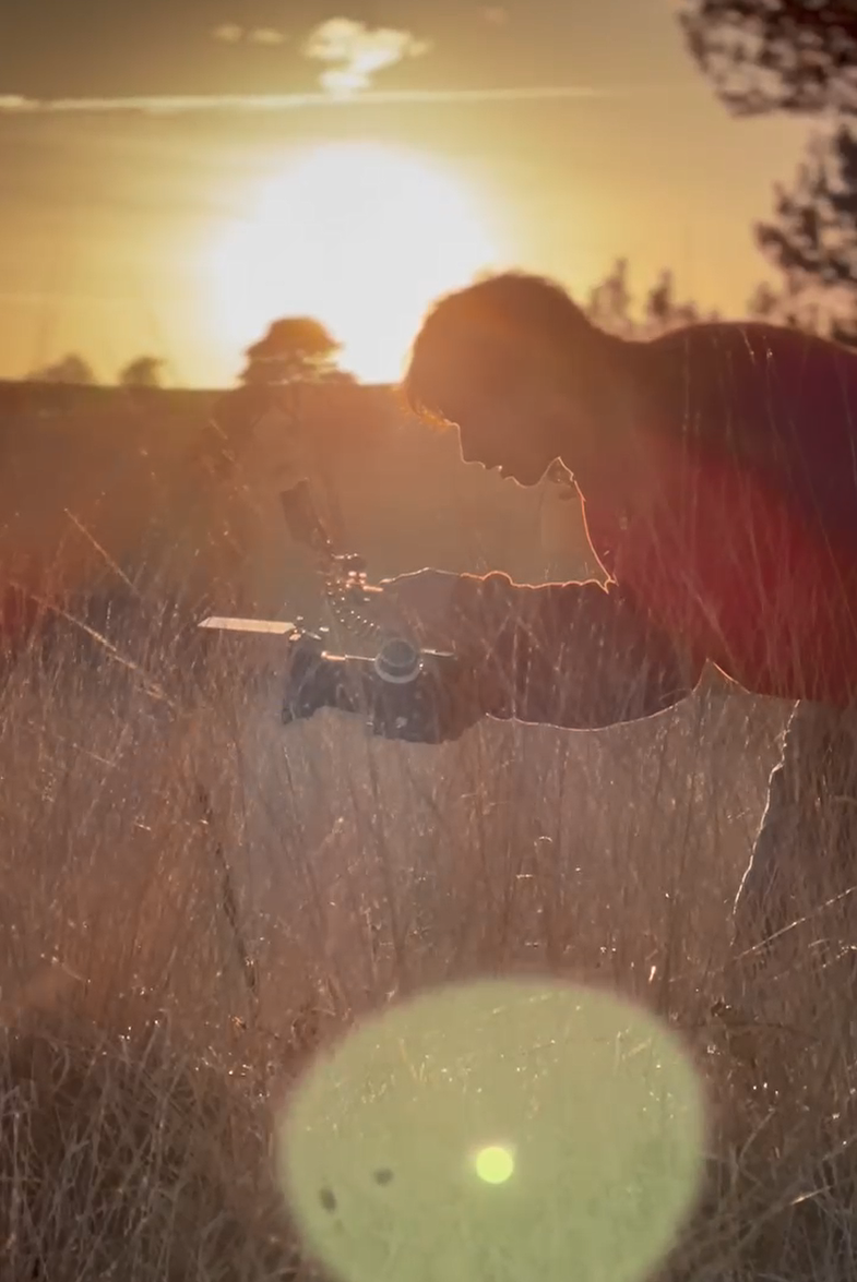 Thomas Wilson with camera in a golden field at sunset