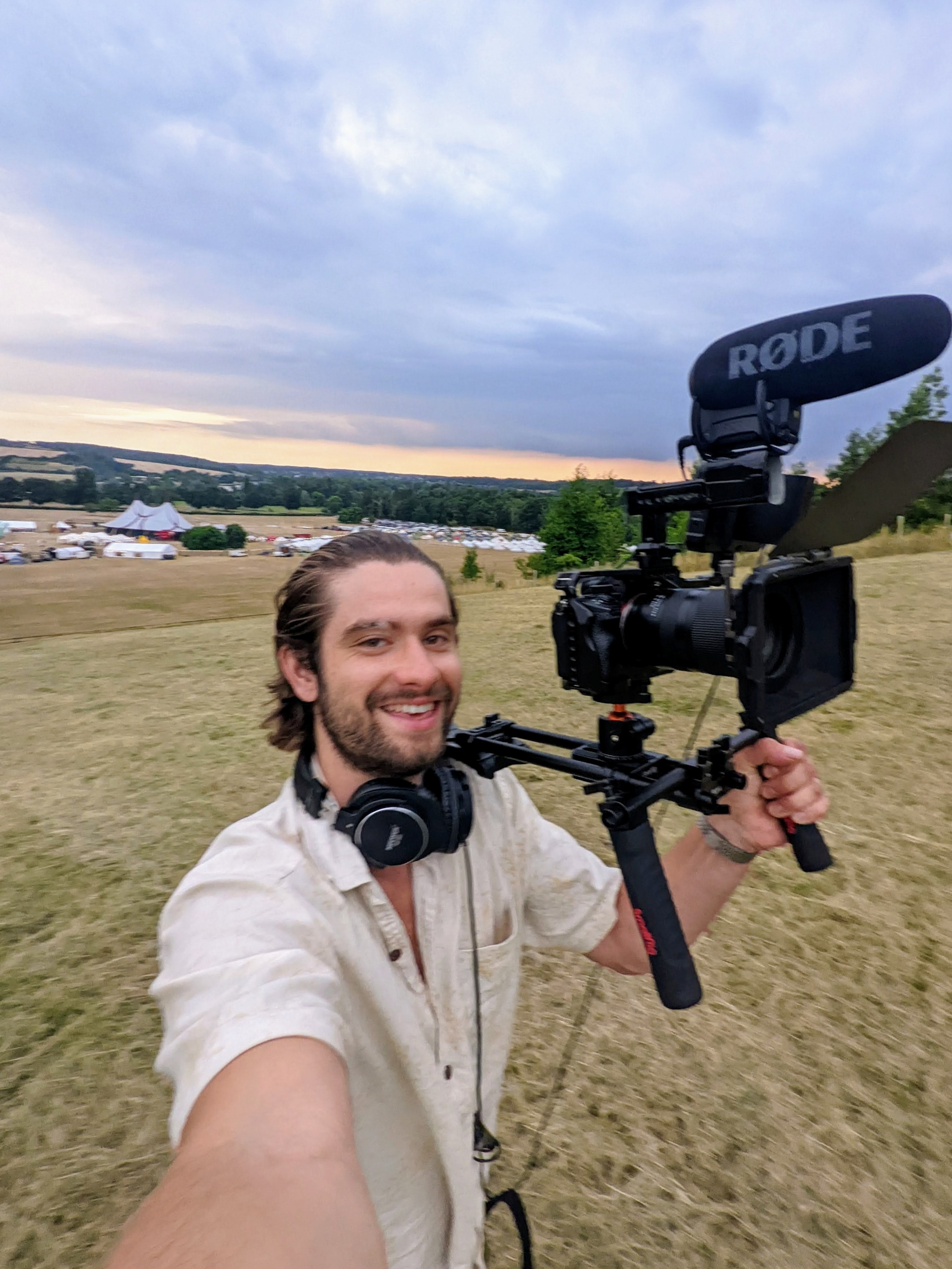 Thomas Wilson holding camera rig at a festival at sunset